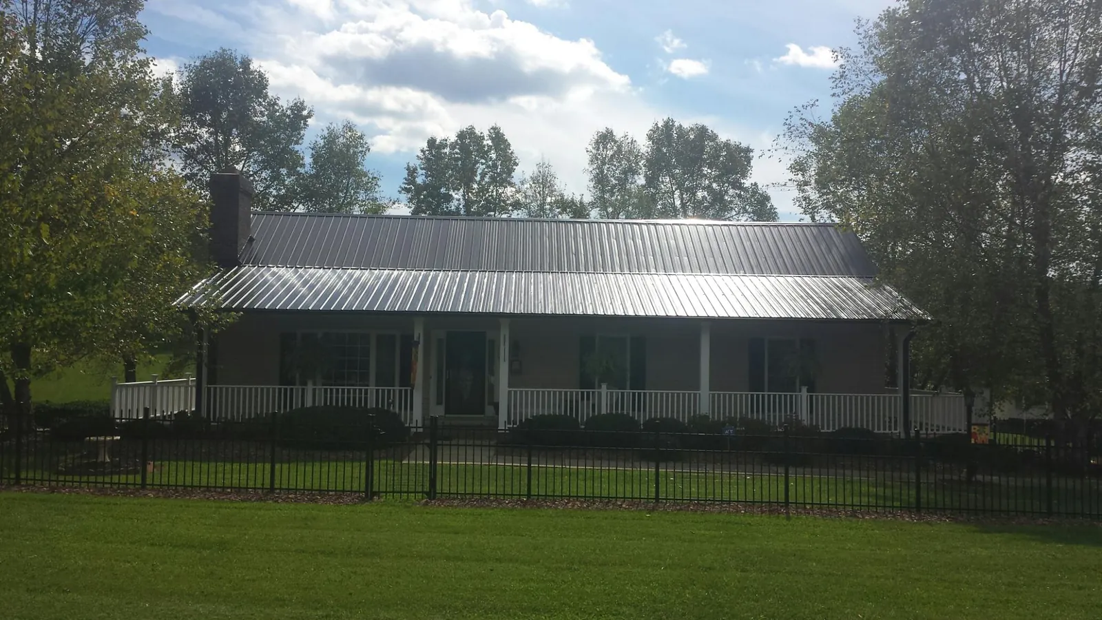 Gray metal roof on a brick ranch with a full width front porch — Gutter Guard Installation work by our crew in Clinton